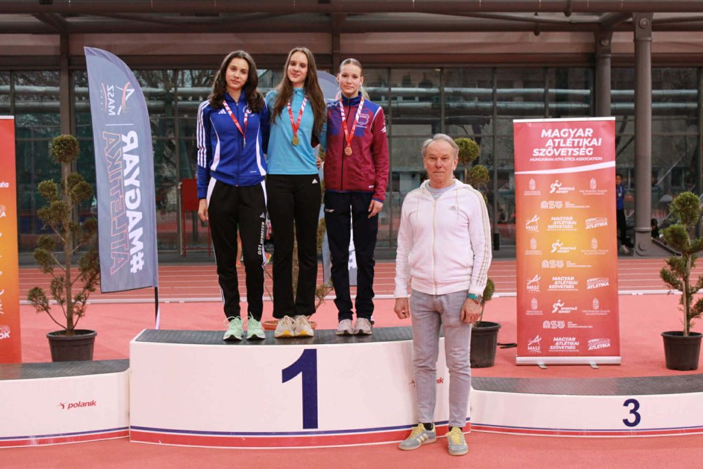 Enyedi Lili Nyíregyházán, a bajnoki dobogó tetején, edzője, László István a dobogó mellett.